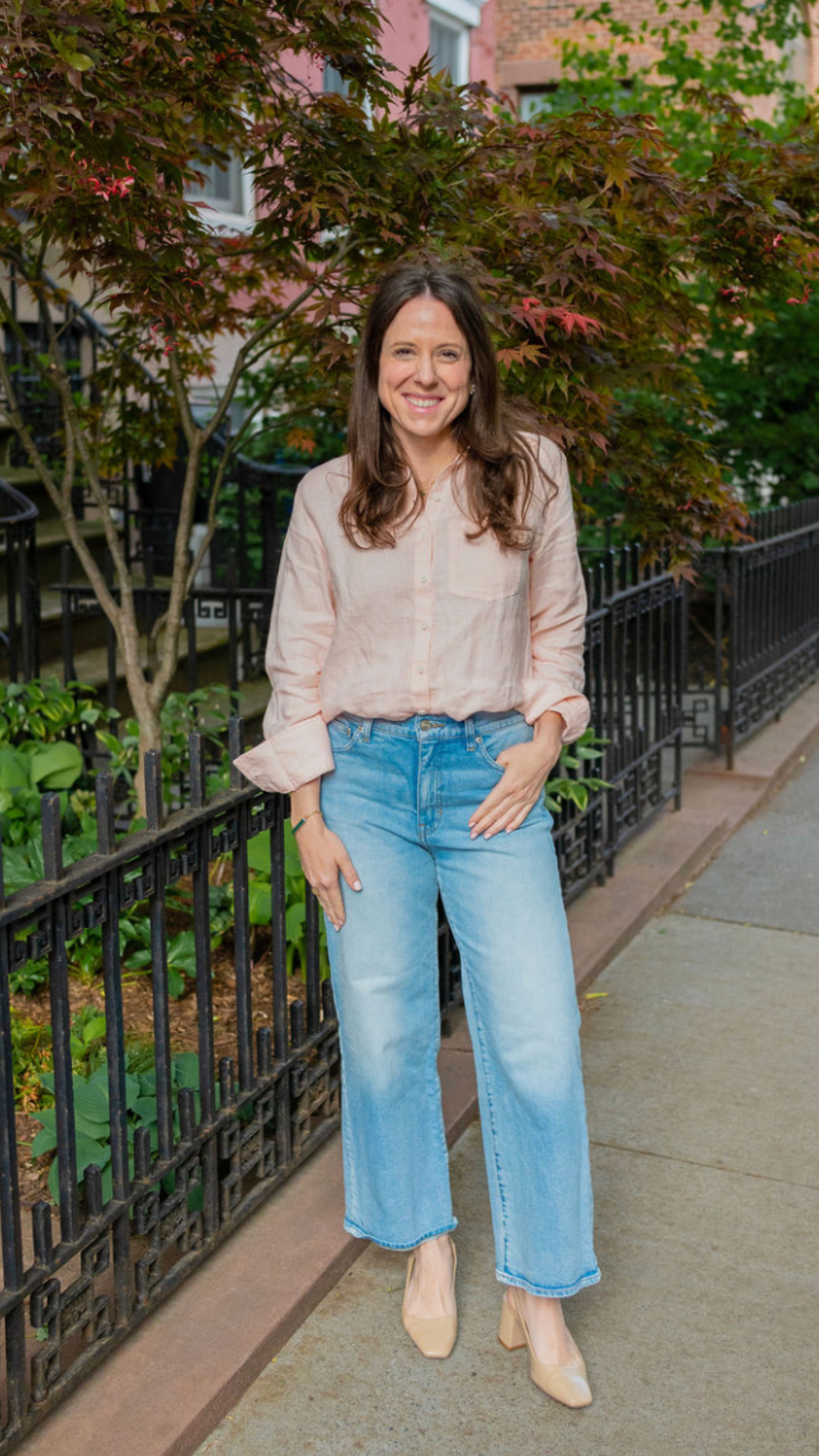 Elizabeth standing on a Brooklyn sidewalk in a pink shirt and jeans